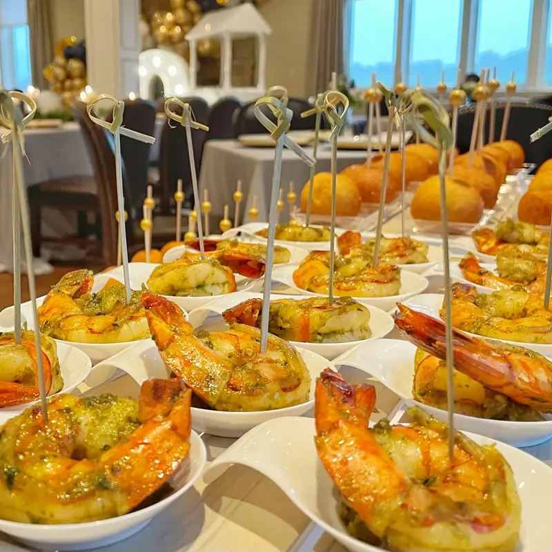 Rows of shrimp appetizer cups on skewers at a catered event