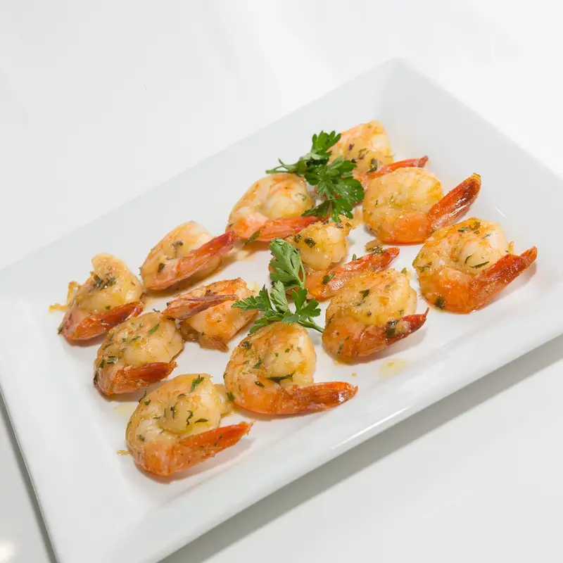 Garlic butter shrimp with fresh parsley on a white platter