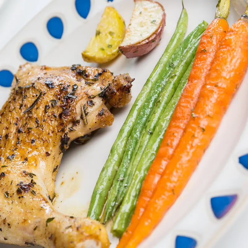 Close-up of herb-roasted chicken with carrots and green beans