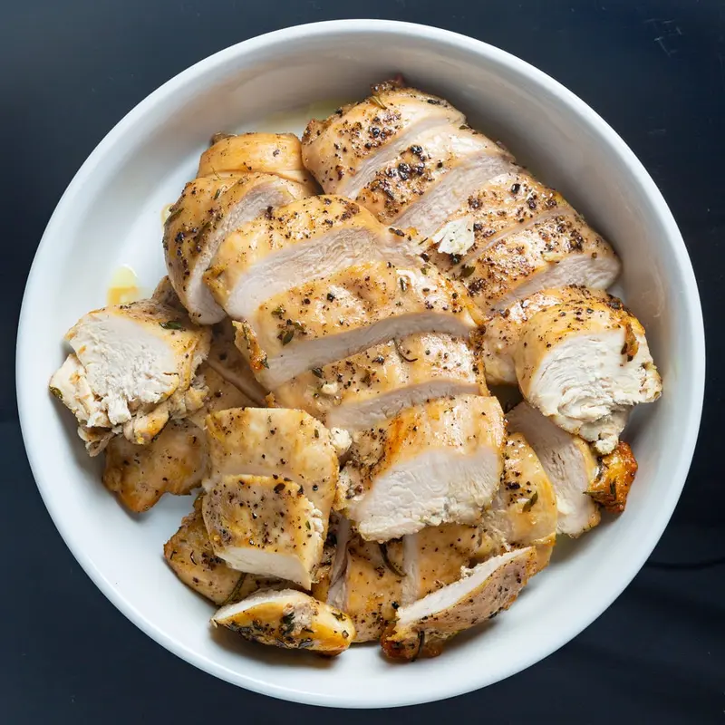 Sliced oven-roasted chicken breast in a white bowl