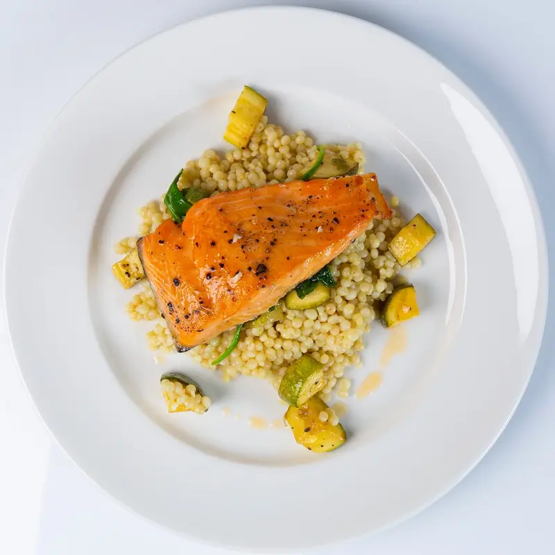 Salmon fillet over pearl couscous with zucchini and squash