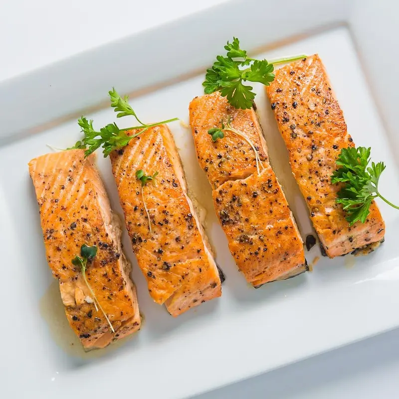 Four pan-roasted salmon fillets on a serving platter
